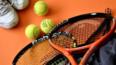 Dos raquetas de tenis con pelotas sobre el suelo del campo
