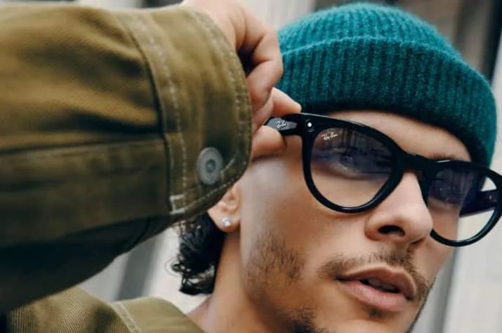 Primer plano de un hombre ajustando sus gafas inteligentes Ray-Ban Meta con montura negra y cristales ligeramente tintados.