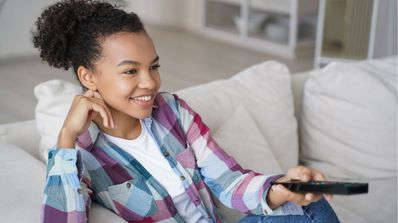 Una chica sonríe mientras sujeta el mando de la televisión