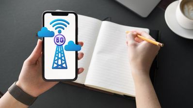 Tomando notas en un cuaderno mirando un móvil con 5G