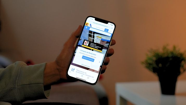Persona sosteniendo un teléfono móvil con la página web oficial de la Seguridad Social abierta en el navegador.
