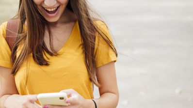 Una chica de Embou mirando el móvil con felicidad