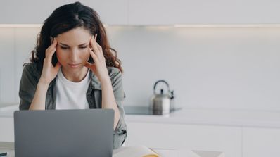 Una chica con dolor de cabeza delante del ordenador portátil
