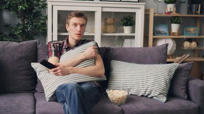 Un chico viendo la tele en el sofá con cara de tensión