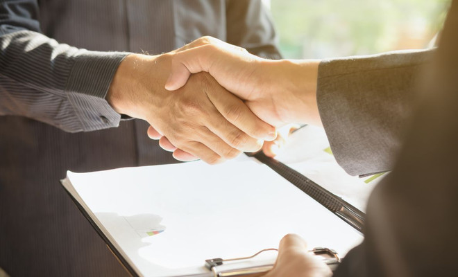Dos ejecutivos dándose la mano firmando un contrato