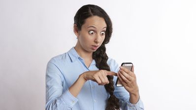 Una chica muy sorprendida mientras mira su móvil