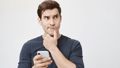 Hombre pensando con móvil en la mano