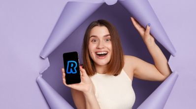 Una chica saliendo de la pared con un móvil de Revolut