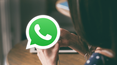 Una persona sostiene un smartphone mientras configura la verificación en dos pasos en la pantalla de WhatsApp.
