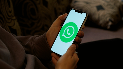 sujetando un smartphone con el logo de WhatsApp