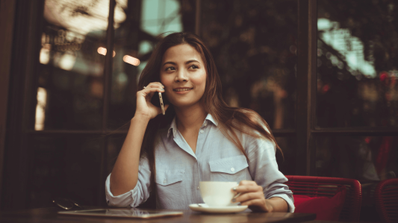 Chica habla por el móvil en una cafetería