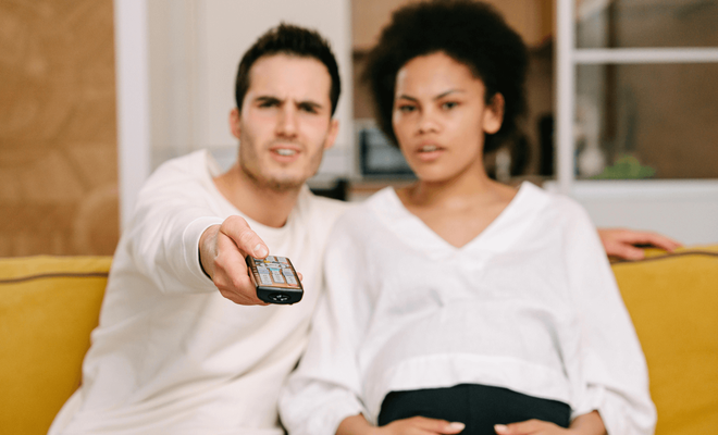 Pareja viendo la televisión con interés y cambiando de canal