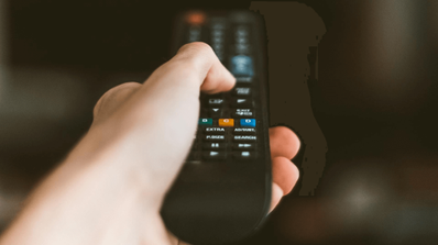 Usuario navegando por la guía de canales de Movistar Plus+ con un mando a distancia, buscando la oferta de la BBC.