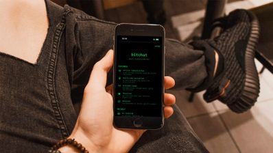 Interfaz de la aplicación de mensajería Bitchat en un smartphone, mostrando una lista de contactos y una conversación activa en una red mesh.