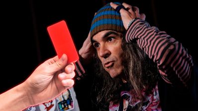Chema Alonso, experto en ciberseguridad, sonríe mientras sostiene una tarjeta roja simbólica durante una ponencia sobre tecnología y ética en el deporte.