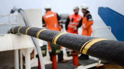 Técnicos en un buque cablero especializado desplegando un cable de fibra óptica submarino en alta mar