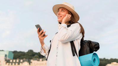 Mujer en una playa consultando su smartphone, ilustrando el concepto de tener conexión a internet durante los viajes de vacaciones