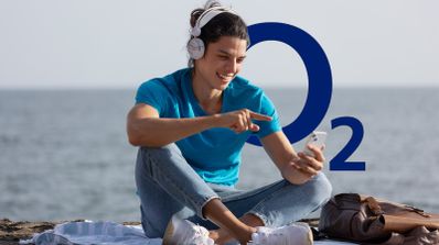 Hombre joven usando su smartphone con el logo de O2, ilustrando cómo gestionar el consumo de datos móviles en la operadora.