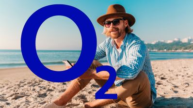Un usuari sonríe mientras habla por su teléfono móvil en una playa soleada, ilustrando el concepto de conectividad de O2 en segundas residencias durante el verano.