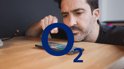 Hombre joven en una playa consultando su consumo de datos en un smartphone con la app de O2 para optimizar su tarifa durante las vacaciones