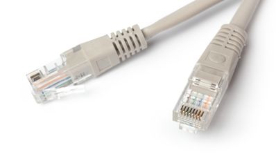 Primer plano de un conector de red RJ-45 insertado en el puerto Ethernet de un dispositivo, con el cable azul saliendo de un tubo corrugado blanco en la pared