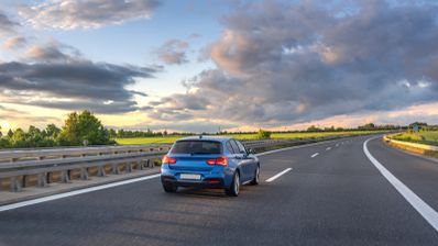 Coche azul circulando por el carril izquierdo de una carretera
