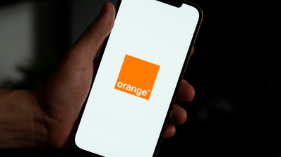 Smartphone mostrando la aplicación Mi Orange junto a un icono de señal WiFi, representando el servicio WiFi Premium para optimizar la red del hogar