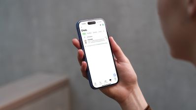 Mano de una mujer sosteniendo un iPhone 16 con la aplicación de WhatsApp abierta, ilustrando el concepto de Modo Agenda para organizar tareas