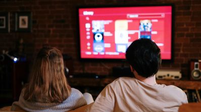 Familia disfrutando de contenido en streaming en su televisor en un salón moderno, ilustrando el uso de un paquete convergente de TV y conectividad