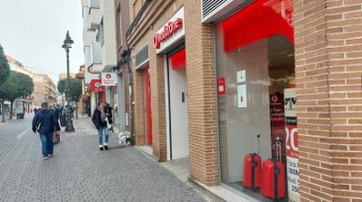 Fachada de una tienda comercial de Vodafone a pie de calle, con el logotipo corporativo rojo sobre la entrada