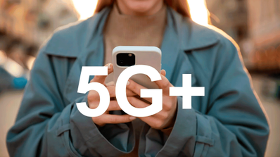 Persona utilizando un smartphone en un entorno urbano con el icono de red 5G+ visible en la pantalla, ilustrando la compatibilidad del dispositivo.