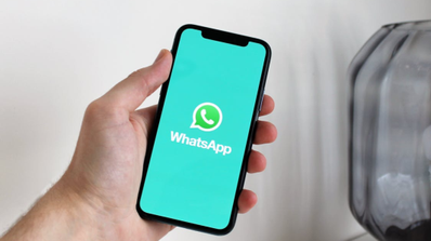 Imagen con persona con móvil con logo WhatsApp en la mano