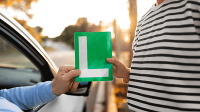 Un conductor que se acaba de sacar el carnet de conducir recibiendo la L de conductor novel