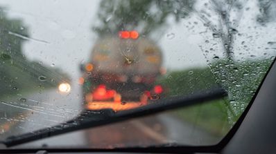 Vista desde el interior de un coche conduciendo bajo una lluvia intensa, mostrando la reducción de visibilidad a través del parabrisas con gotas de agua