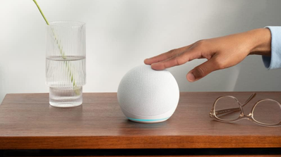 Primer plano del altavoz inteligente Amazon Echo Dot de 5ª generación en color antracita, con una persona interactuando con los botones superiores