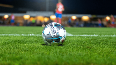 Un balón de fútbol con un jugador en el fondo de la foto