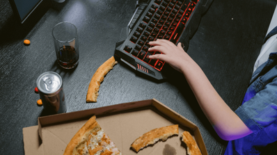 Jugando en el ordenador con juegos y pizza