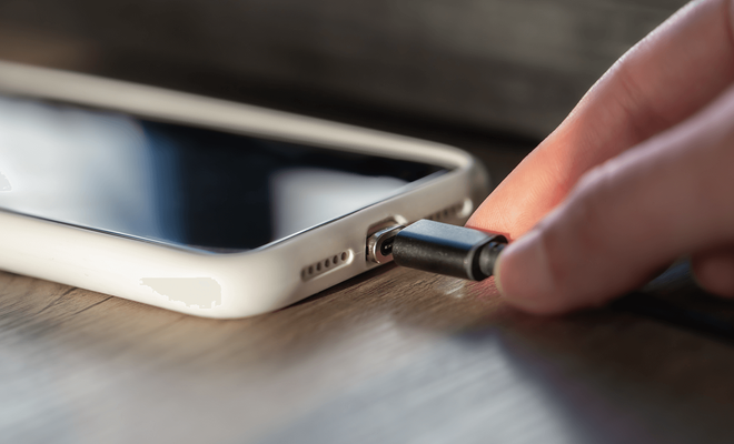 Hub USB-C magnético de color gris espacial conectado a la parte trasera de un smartphone Android, mostrando sus múltiples puertos: HDMI, USB-A y lector de tarjetas SD
