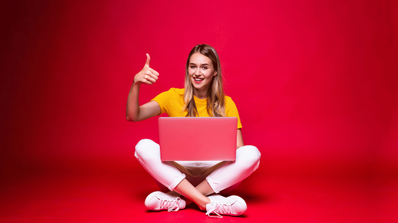 Mujer joven con PC y el pulgar hacia arriba
