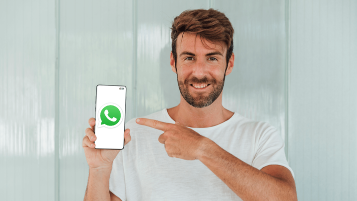 Hombre joven consultando la pantalla de su smartphone donde se ve la interfaz de la aplicación WhatsApp