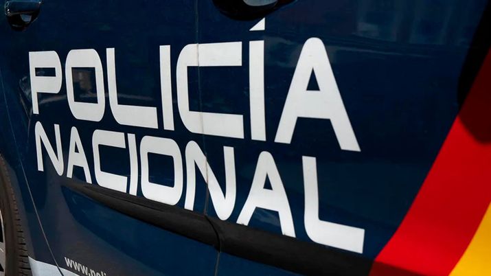 Primer plano del lateral de un vehículo de la Policía Nacional de España con el rótulo oficial sobre la carrocería azul.