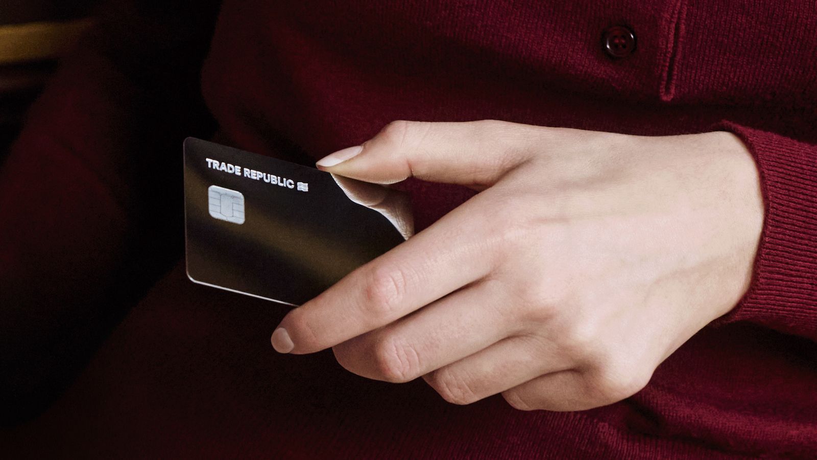 Primer plano de una mano sosteniendo una tarjeta bancaria de color negro con el logotipo de Trade Republic.
