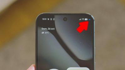 Primer plano de la parte superior de un smartphone Android con una flecha roja indicando un pequeño punto azul en la barra de estado junto a los iconos de cobertura y batería.