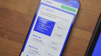 Primer plano de un teléfono móvil mostrando la web de Digi con tarifas de móvil 5G y gigas ilimitados sobre una mesa de madera.