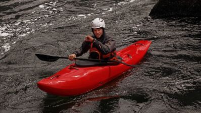 Deportista en un kayak rojo sobre aguas bravas consultando su reloj inteligente Garmin Fenix 8 Pro.