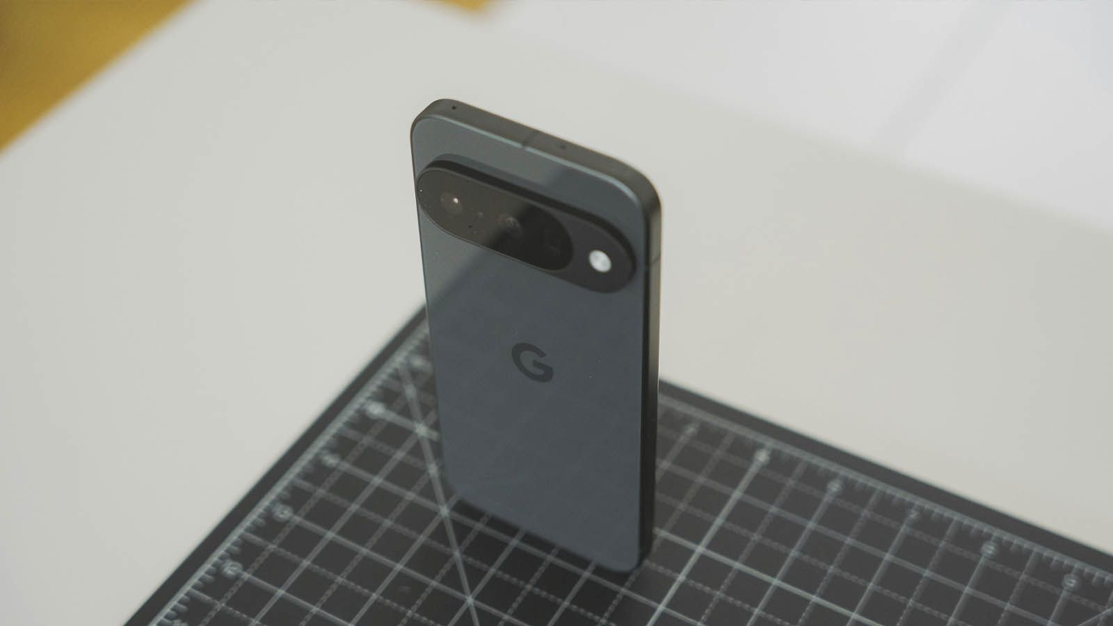 Parte trasera de un teléfono móvil Google Pixel en color oscuro apoyado verticalmente sobre una alfombrilla de corte graduada.