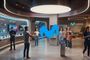 Interior de una tienda de Movistar con empleados atendiendo a clientes y exposición de dispositivos electrónicos bajo iluminación circular.