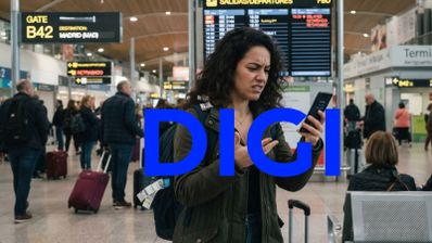 Mujer con gesto de preocupación consultando su teléfono móvil en la terminal de un aeropuerto con maletas y paneles de vuelos al fondo.