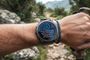 Reloj inteligente Garmin Fenix 8 en la muñeca de un senderista mostrando una actualización de software en curso.