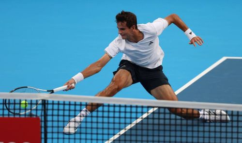 Rafael Jódar realizando un golpe de derecha en una pista de tenis azul tras un desplazamiento lateral.